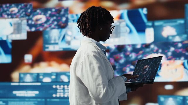 Epidemiologist reviewing viral mutation models on notebook screen. Scientist analyzing 3D virus structure on laptop to support vaccine development, surrounded by medical dashboards, camera B