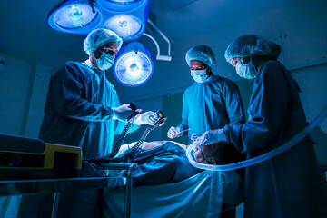 Team of surgeon doctor using defibrillator to give electrical shock to patient heart who is suffering from cardiac arrest in emergency surgical room for healthcare