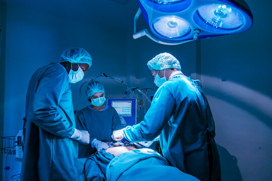 Team of surgeon doctor using defibrillator to give electrical shock to patient heart who is suffering from cardiac arrest in emergency surgical room for healthcare