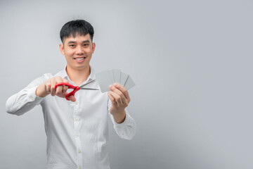 A handsome Asian businessman expresses satisfaction while cutting credit card with red scissors. This concept is suitable for themes of financial freedom, debt reduction, business, and advertising.

