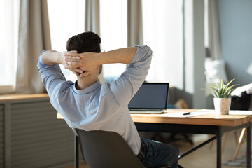Rear view relaxed businessman reclining back on chair before laptop