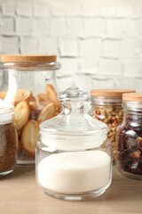 Glass jars with different products on wooden table, closeup