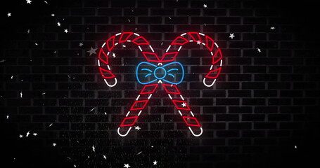 Image of neon candy canes christmas decoration over stars falling on black background