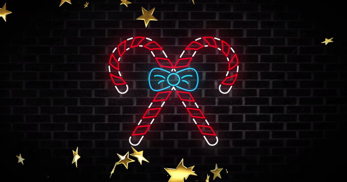 Naklejki Image of neon candy canes christmas decoration over stars falling on black background