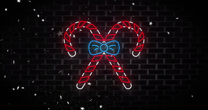 Image of neon candy canes christmas decoration over stars falling on black background