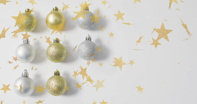 Naklejki Image of christmas baubles over floating stars on white background
