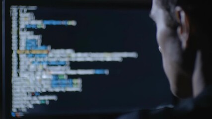 Focused man coding, working with computer, programming code on screen in dark room, software development and technology concept. - Powered by Adobe