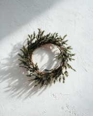 Minimalist Christmas wreath with frosted leaves on white wall, editorial holiday decor photo highlighting elegance, purity, and the calm aesthetic of winter interior design culture