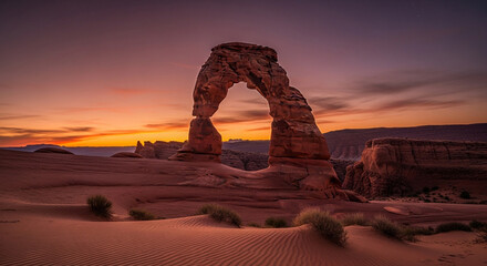 Majestic delicate arch at sunset, bathed in warm light, stands proudly amidst the rugged terrain of arches national park, utah, showcasing natures artistry