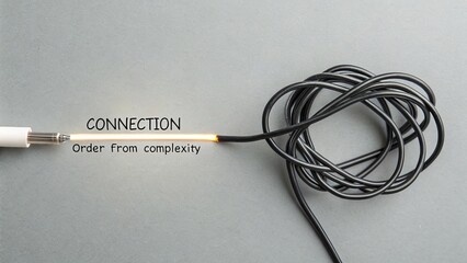 Black electric cable forming a tangled knot on a gray background