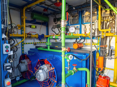 Gas distribution unit. Industrial gasification equipment. Gas boiler with pipes and pumps. Propane-powered electric generator at factory. Iron container with gas and power equipment.