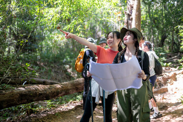 Young women friends exploring forest hiking trail with map
