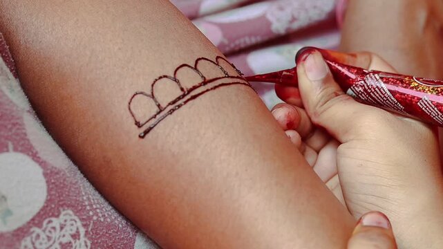 A person applying simple mehndi design on hand using a cone, traditional henna art for festivals and celebrations