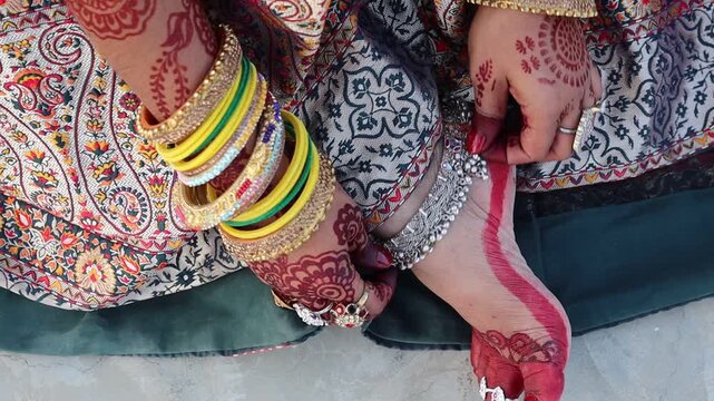 Indian woman wearing colorful bangles and anklets, dressed in traditional attire for festive celebrations like marriage, Teej, or Karwa Chauth