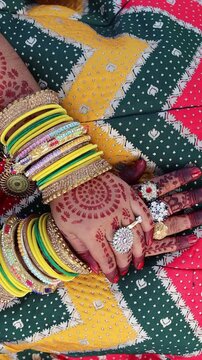 Close up video of Indian woman's hands featuring beautiful intricate mehndi design, colorful glass bangles and gold rings, traditional ethnic fashion and wedding concept.