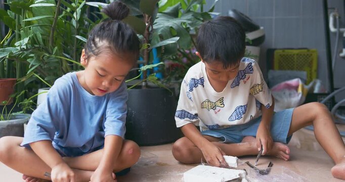 Adorable little boy and girl enjoy dig dinosour fossil toy kids sciene learnning