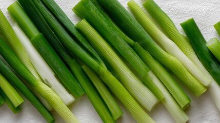 Obraz premium Freshly sliced leeks arranged neatly on a white surface for cooking preparation