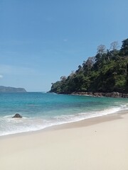 Thailand's tropical coastline offers a stunning summer vacation paradise with turquoise sea water, white sand, palm trees, and a clear blue sky