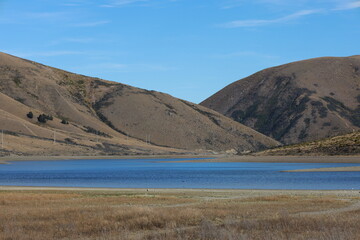 Dry hills and blue lake scenery near Castle Hill (Kura Tawhiti), Canterbury, South Island, New Zealand, captured in May 2025 during a scenic ride through the high country landscape. © Chonlatit