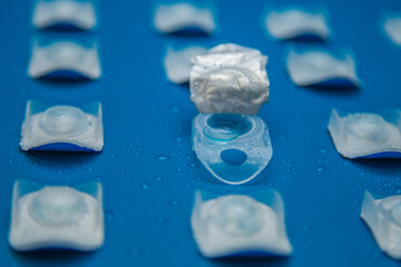 Close-up side view of a container with a contact lens and disposable contact lenses in containers...