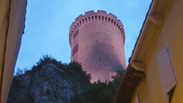 Historic medieval castle tower of Foix standing tall against blue twilight sky, symbol of heritage.