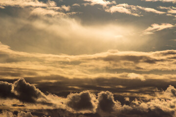 Dramatic golden clouds fill the sky, illuminated by soft sun rays breaking through. An atmospheric weather scene creates a stunning natural background