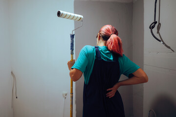 Female Painter Decorator Feeling Pain in her Lumbar Area. Tired worker suffering from work related chronic pain
