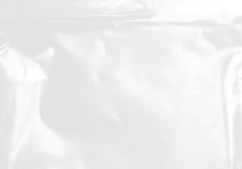 plastic transparent cellophane bag on white background. The texture looks blank and shiny. The plastic surface is wrinkly and tattered making abstract pattern