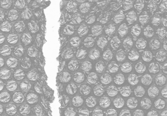 plastic transparent cellophane bag on white background. The texture looks blank and shiny. The plastic surface is wrinkly and tattered making abstract pattern