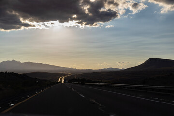 A long highway stretches to the horizon under a dramatic sky