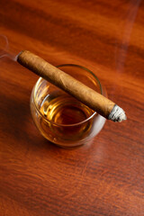 bourbon in a glass on an old wood table with smoking cigar