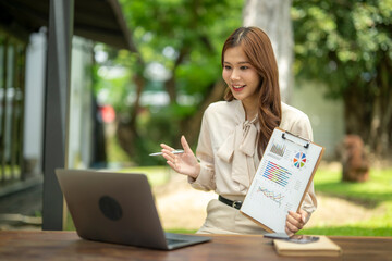 Asian businesswoman having video call showing financial charts