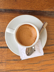 directly above shot of  macchiato cup of coffee with spoon a sachet of sugar on wooden table