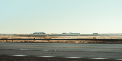 Highway stretches through a hazy, arid landscape.  Dark piles of material are visible in the distance