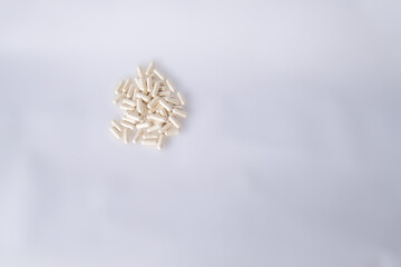 White capsules for gut health on a white background. There is space for text.