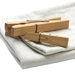 Wooden clothespins rest on folded white cloth.