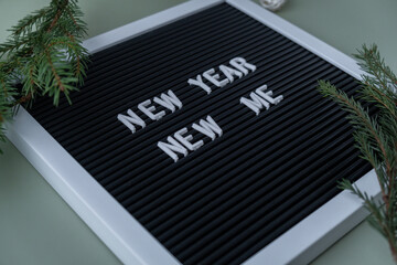 Letter board with inspirational message NEW YEAR NEW ME with fir branches on pastel background. Happy new year promises resolutions concept. Self growth and personal development
