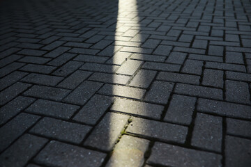 Fototapeta premium Sunlight Streaming Through a Narrow Gap on Patterned Brick Pavement