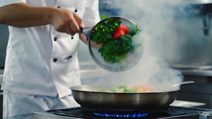 Chef tossing fresh colorful chopped vegetables into a steaming frying pan over a blue gas flame in a commercial kitchen - Powered by Adobe