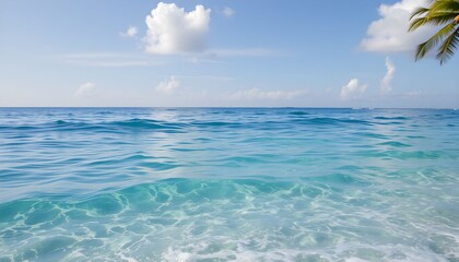 Obraz premium Clear turquoise ocean water gently laps onto a sandy beach under a bright blue sky.