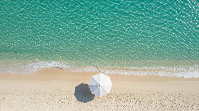 Aerial view of a beach with a white umbrella and turquoise water