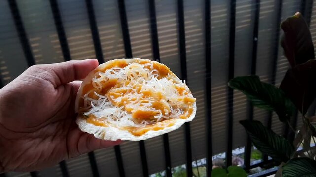 Hand holding Indonesian kerupuk kuah with noodles topping traditional street food