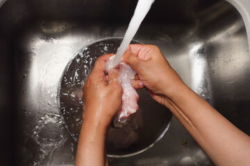 Fototapeta premium Washing chicken in a clear bowl under running water
