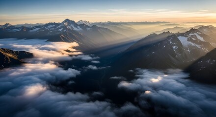 Majestic mountain range with golden sun rays breaking through a sea of clouds at sunrise.