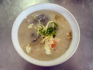 Rice porridge with minced pork and egg is a popular Thai breakfast dish. Egg porridge is a type of Thai dish served in a white bowl with a soft-boiled egg on top. It is a popular breakfast food.