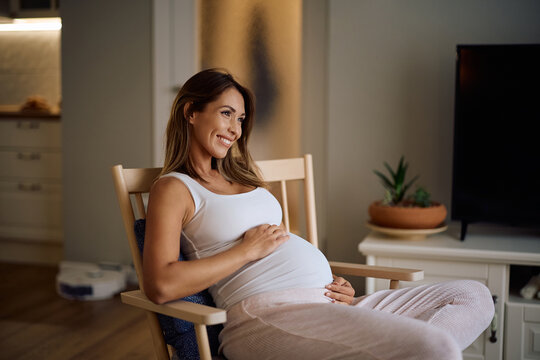 Happy pregnant woman day dreaming while relaxing at home. - Powered by Adobe