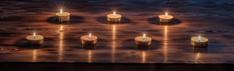 Вurning candles stands on wooden desk in the dark. Template with copy space.