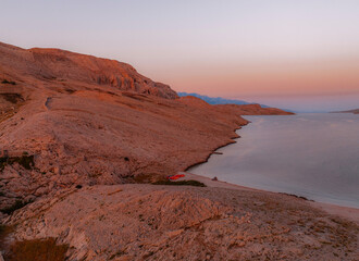 Rucica beach in Metajna on Pag island curved shoreline, crystal-clear turquoise sea, sunlit barren terrain and rocky Adriatic sea