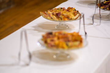 Deliciously prepared savory pies and tarts artfully arranged on a white tablecloth for a catered event or celebration with a focus on exquisite culinary presentation
