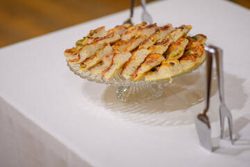 Deliciously prepared slices of savory focaccia bread with olives and herbs displayed elegantly on a clear glass pedestal for a party or special event buffet reception catering spread